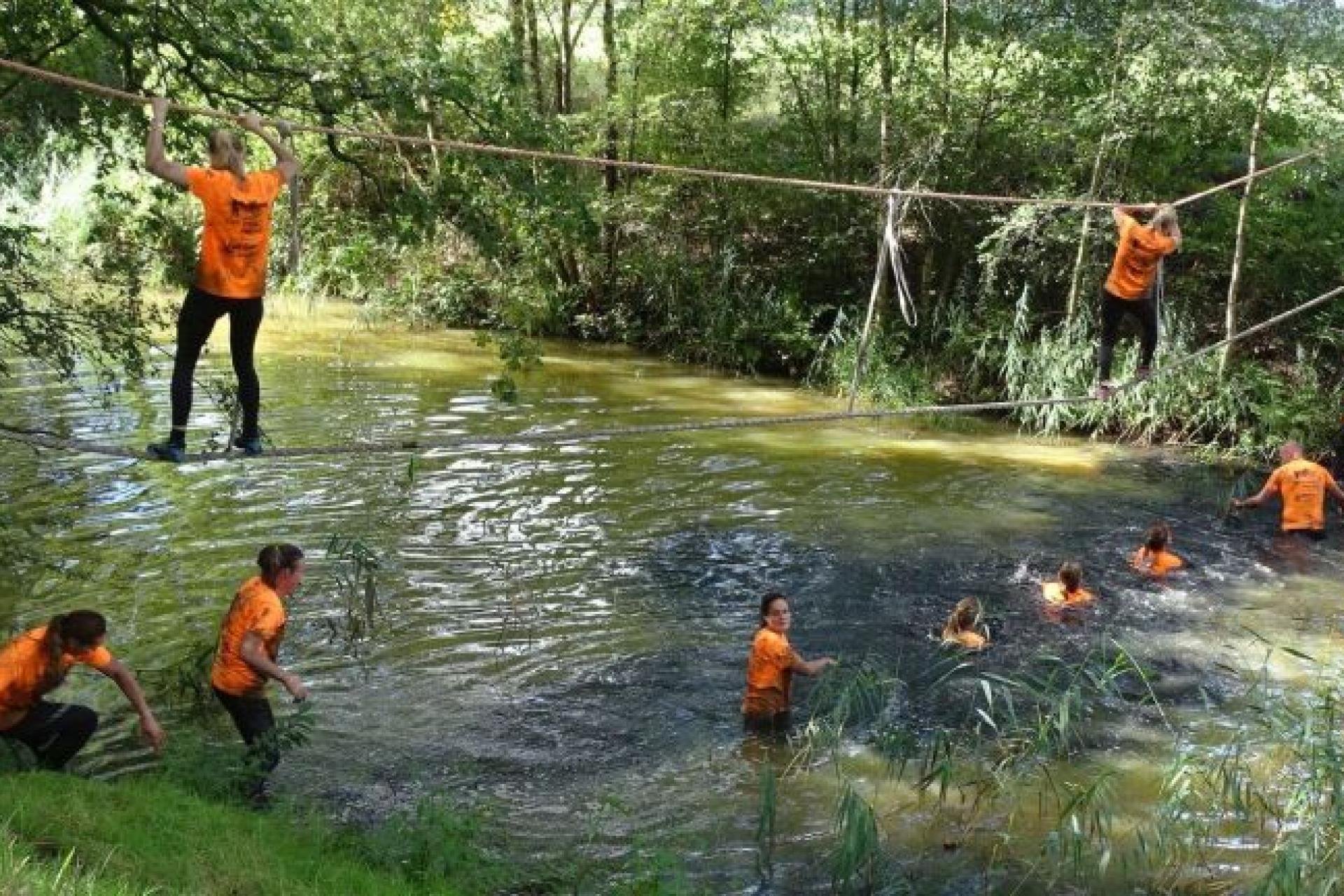 Een groep mensen in een touwenconstructie boven het water