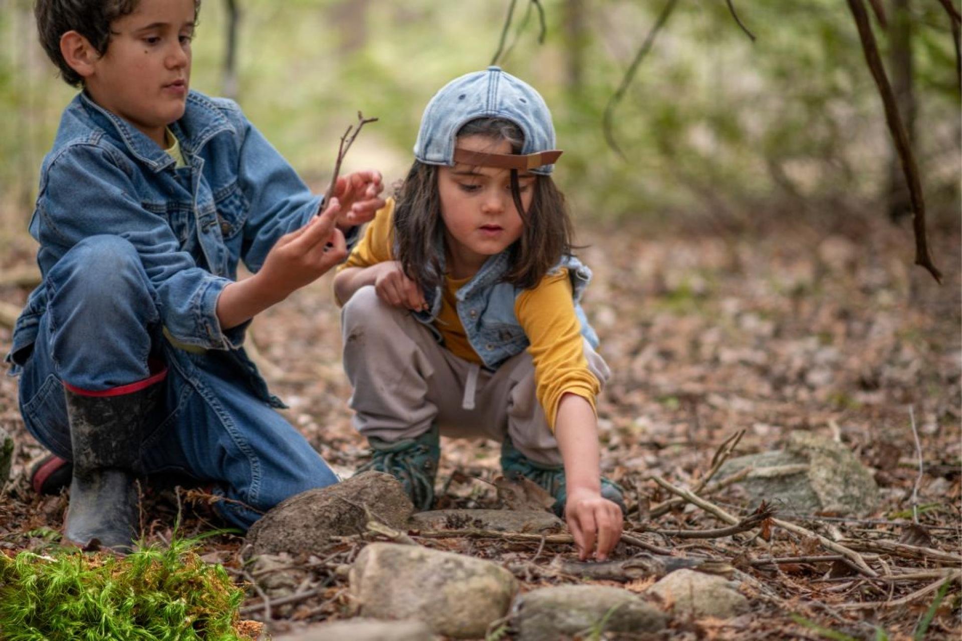 Twee kinderen bouwen een vuurplek in het bos