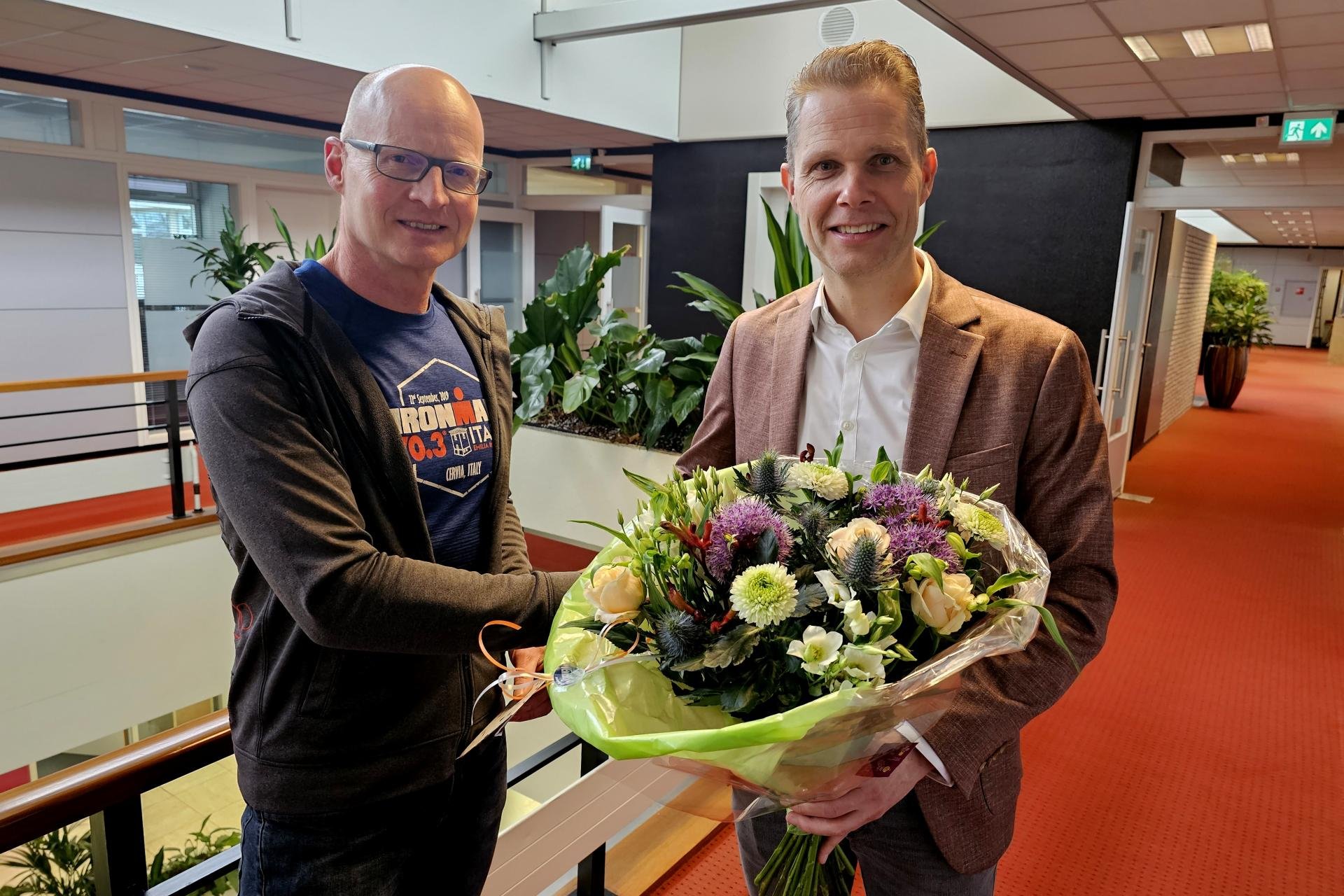 Sportkampioen Theo Fuhler samen met wethouder Pascal Schrik die een bos bloemen in zijn hand heeft